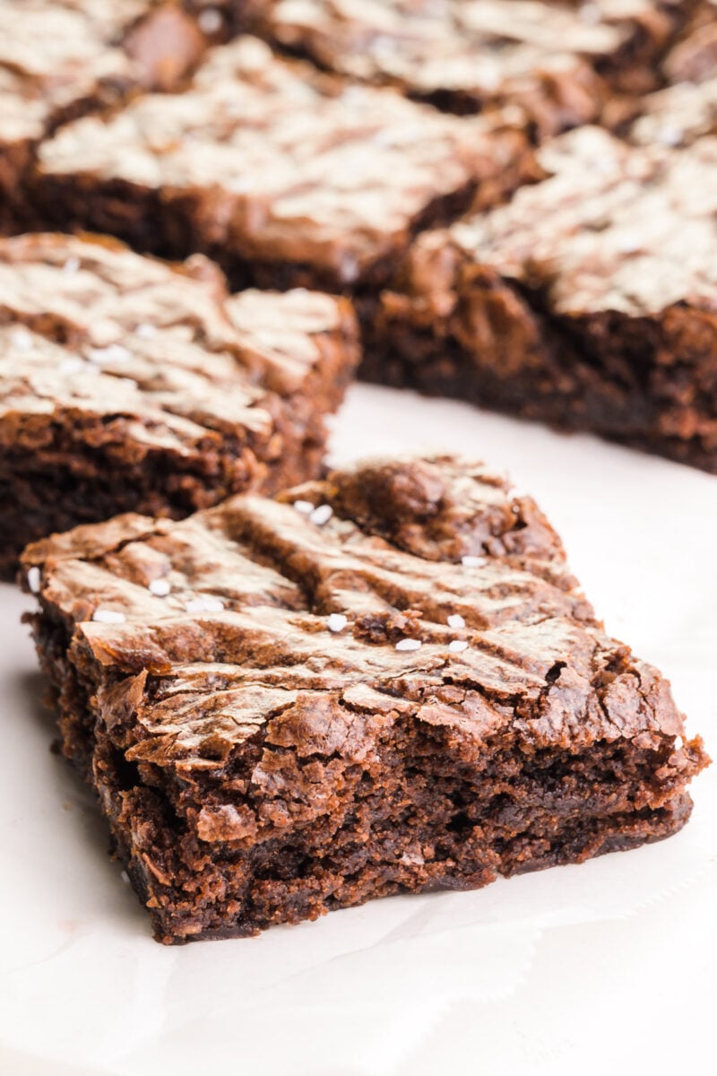 Several brownie slices sit on a white counter top.