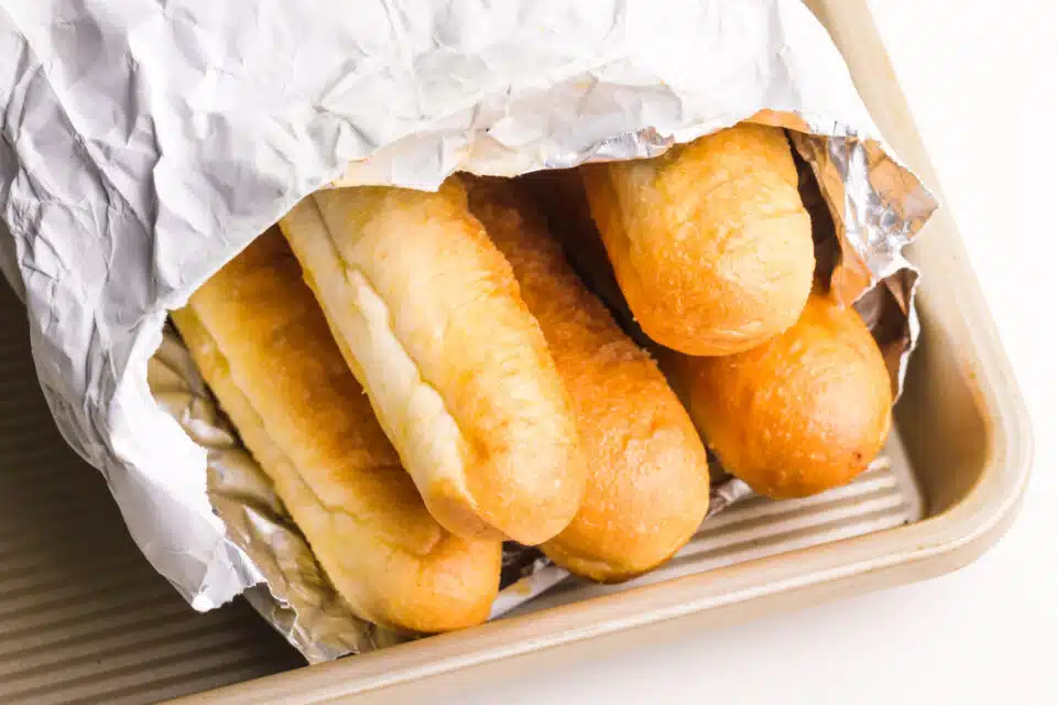 Olive Garden breadsticks are wrapped in foil on a baking dish, waiting to be reheated.