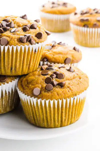 Muffins are stacked on top of each other with more muffins behind them.