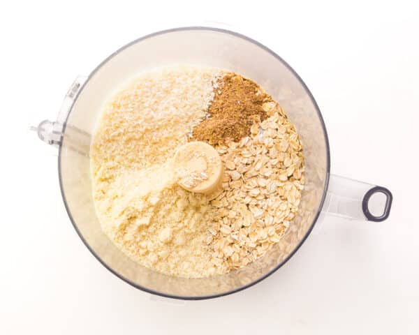 Ingredients are in a food processor, such as ground flax, oats, and almond flour.