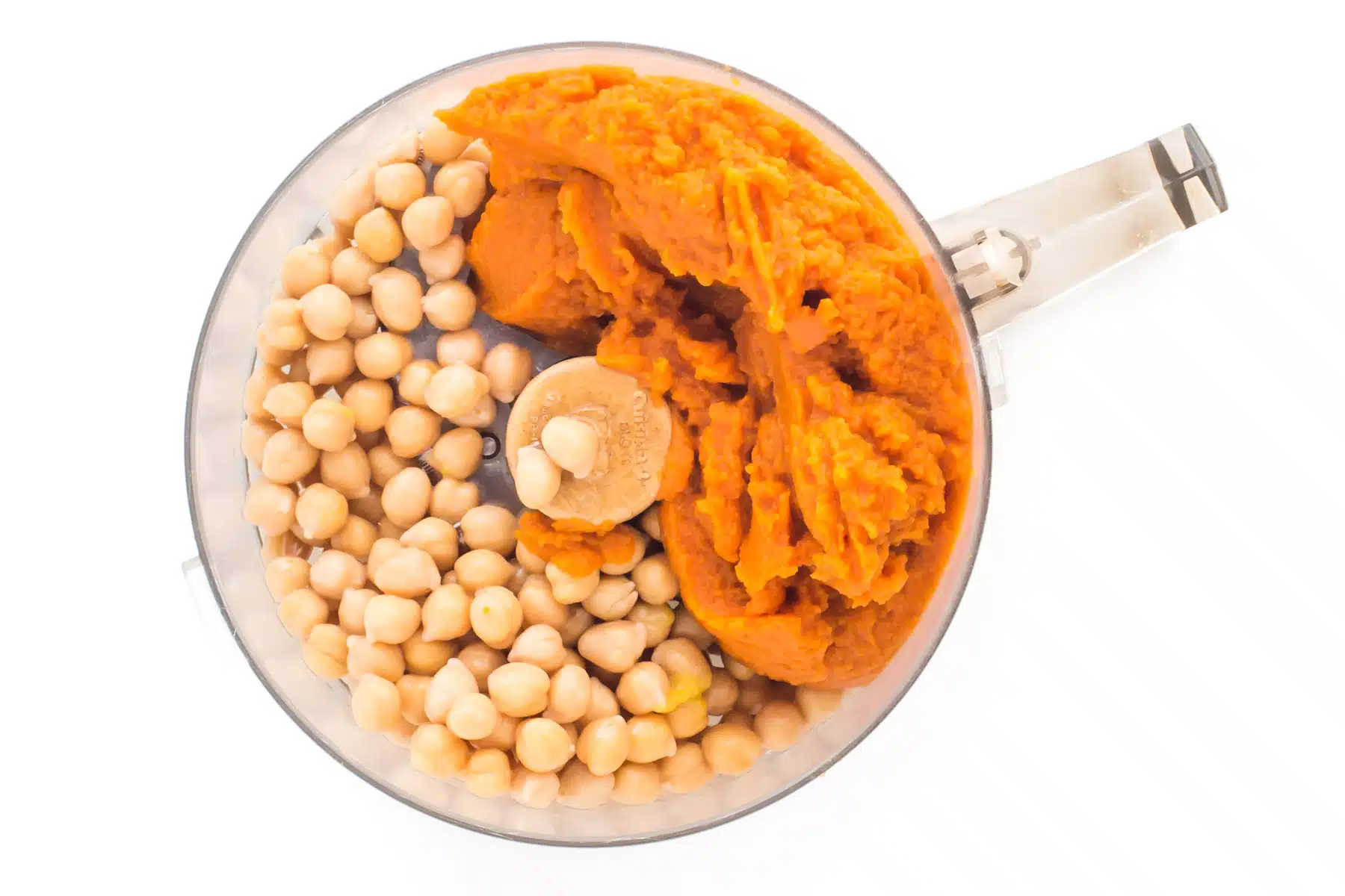Looking down on a food processor full of chickpeas and pumpkin puree.