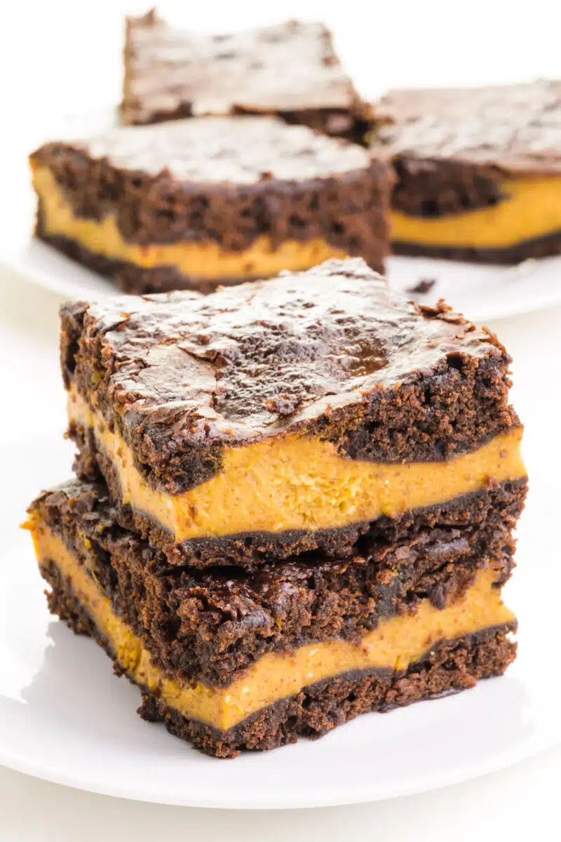 A stack of vegan pumpkin brownies sits in front of more brownies in the background.