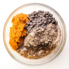 Ingredients are in a mixing bowl, including pumpkin puree, a brownie mix, chocolate chips, and vegetable oil.