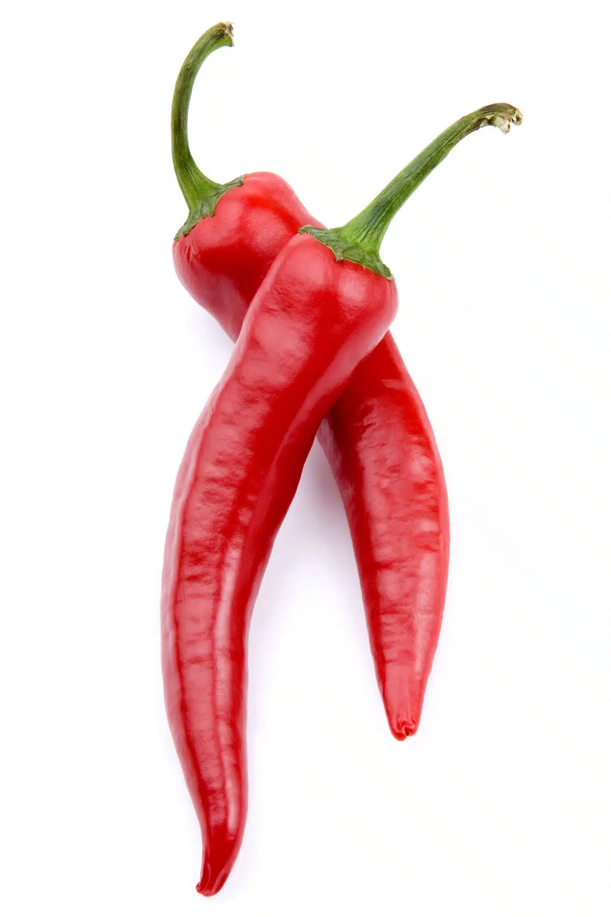 two red chili peppers sit on a white surface
