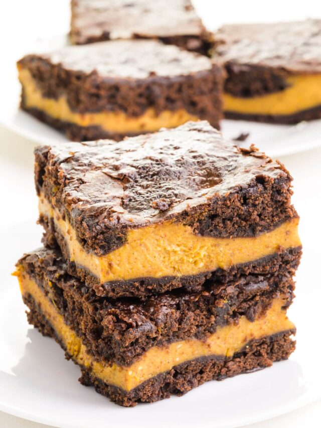 A stack of vegan pumpkin brownies sit in front of more brownies in the background.