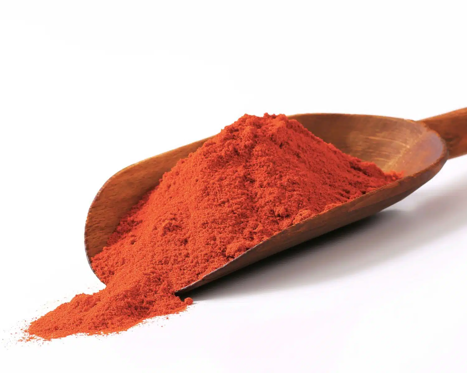 Paprika powder is in a big scoop and scattered out in front of it.