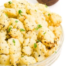 A bowl of air fried frozen cauliflower has fresh herbs on top.