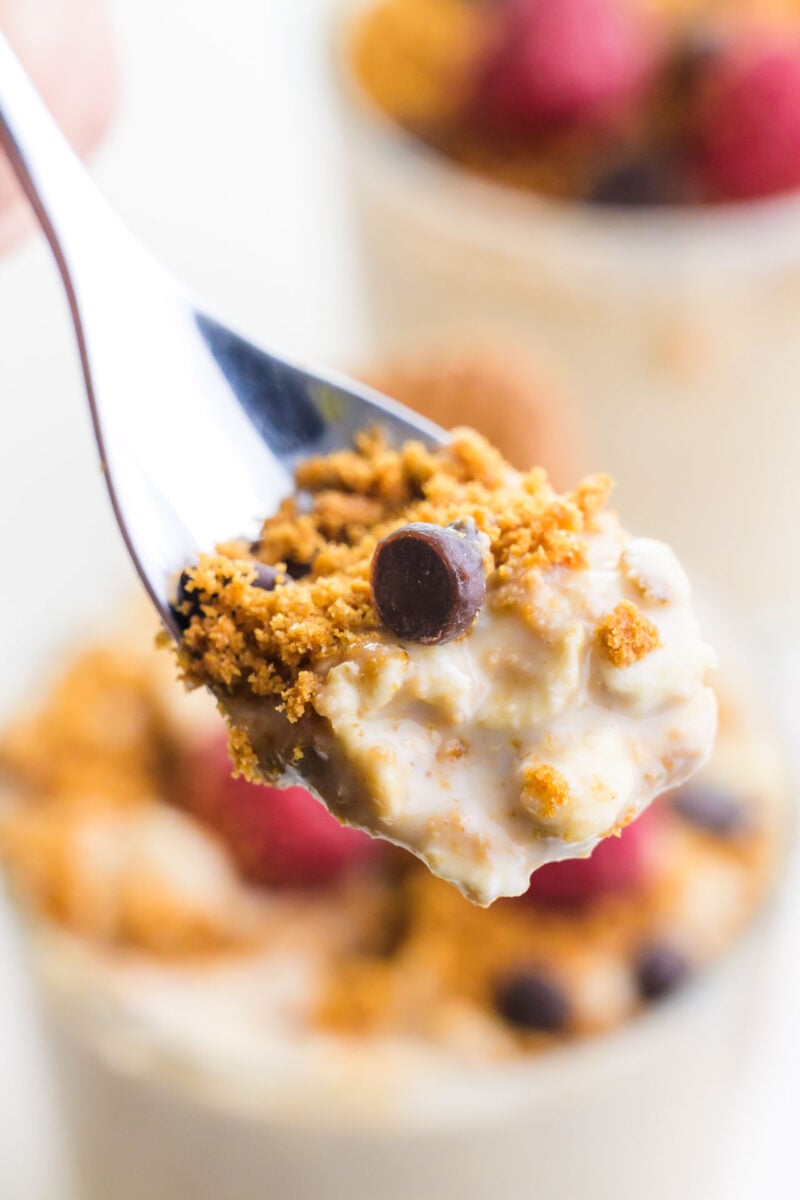 A spoonful of overnight oats hovers in front of a jar with more of the oats in the background.