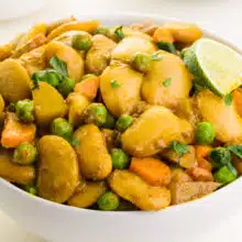 A closeup of butter bean curry in a bowl with a slice of lime on top.
