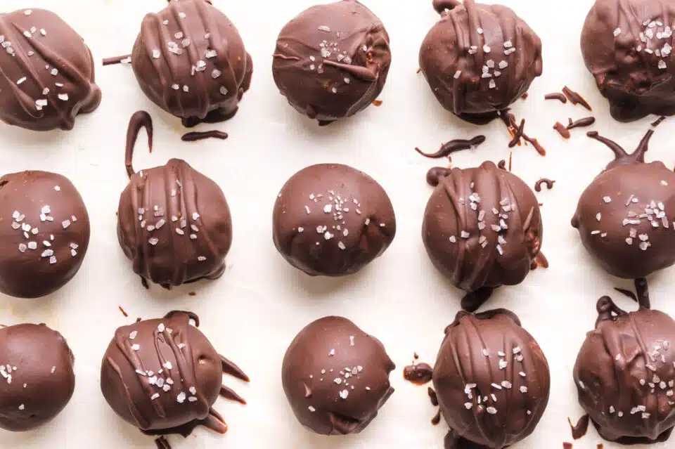 Looking down on cashew butter truffles, dipped in chocolate, and lined up on parchment paper.
