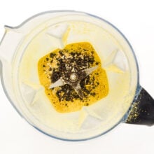 Looking down on a blender with lemon zest, peppercorns, garlic, and more.