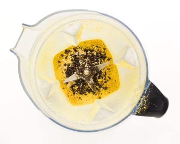 Looking down on a blender with lemon zest, peppercorns, garlic, and more.