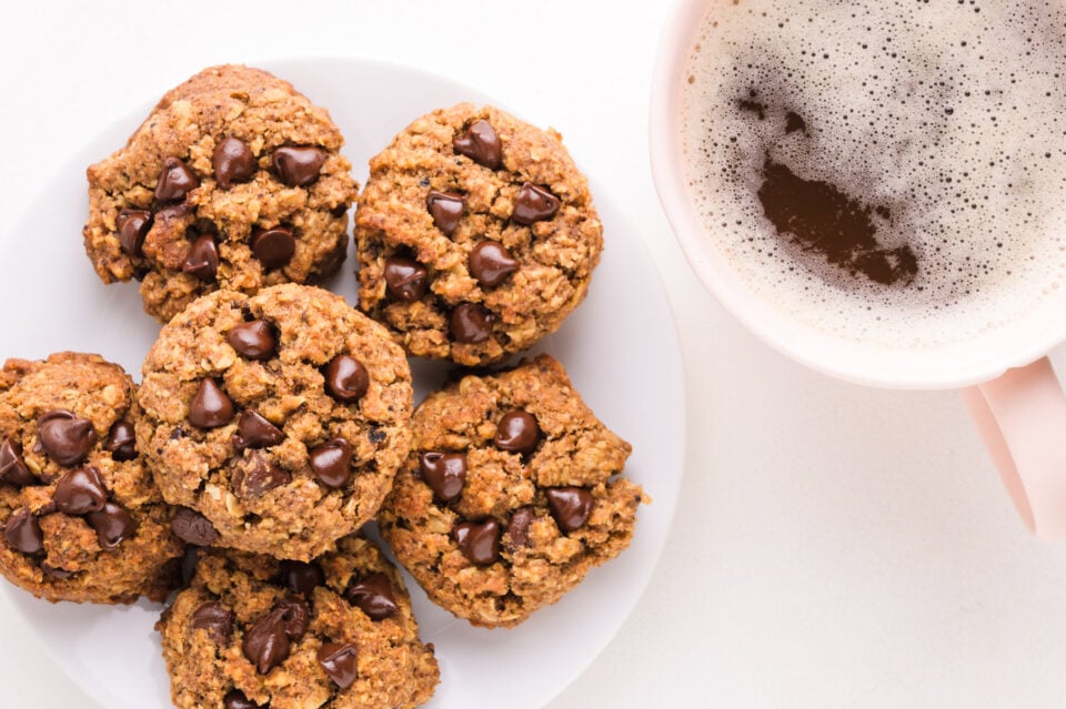 Looking down on a plate oof coffee chocolate chip cookies with a cup of coffee sitting next to it.