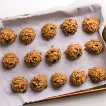 Cookie dough balls are side-by-side on a baking sheet lined with parchment paper.