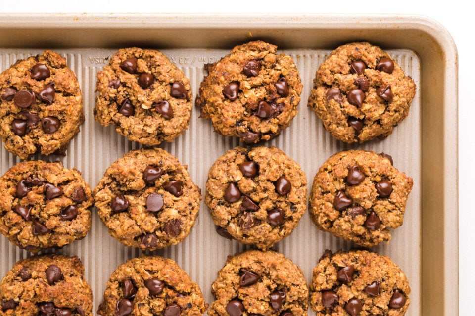 Looking down on a baking tray with rows of chocolate chip cookies.