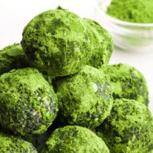 A stack of green spirulina energy balls sits in front of a bowl of matcha tea powder.