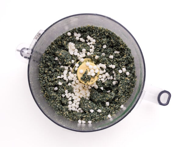 Looking down on ingredients in a food processor bowl, including white chocolate chips.