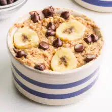 A bowl of vegan baked oats has chocolate chips and banana slices on top.