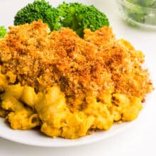 A plateful of vegan chickpea Mac and cheese is on a plate with steamed broccoli.