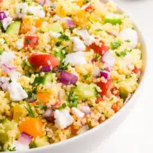 Looking into a bowl of vegan couscous salad with lots of veggies on top.