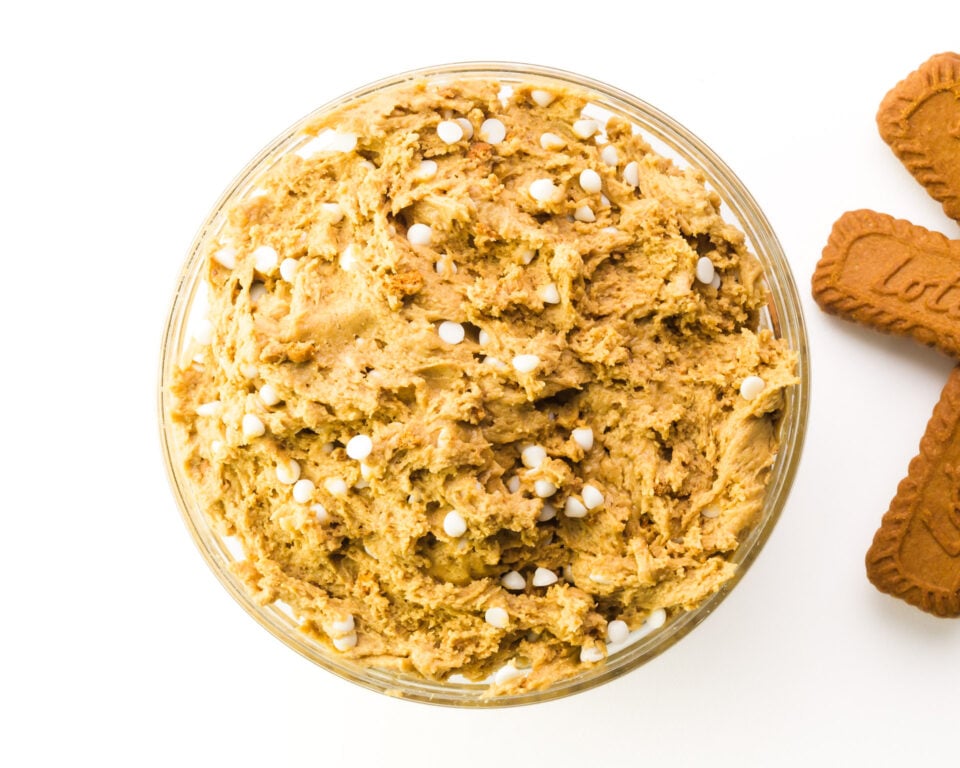 Looking down on cookie dough in a mixing bowl. There are biscoff cookies visible on the right.