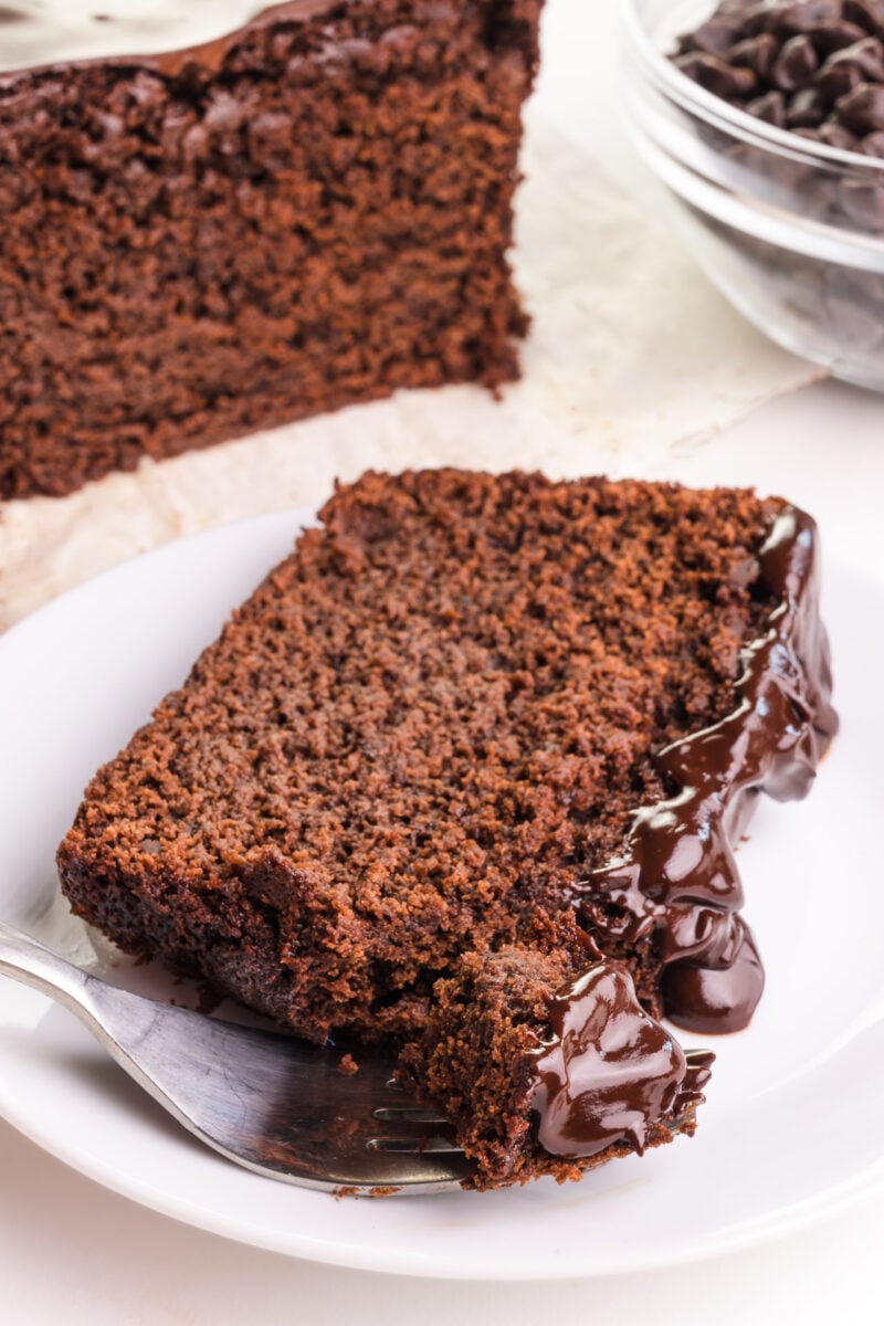 Looking down on a slice of chocolate bread on a plate, sitting in front of the rest of the loaf.