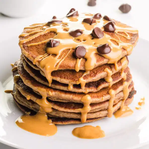 A stack of pancakes has peanut butter and chocolate chips on top.