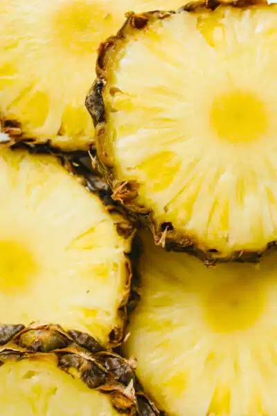 A closeup of pineapples cut into slices with the skin.