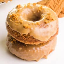 A stack of plant-based biscoff donuts sits in front of biscoff cookies.