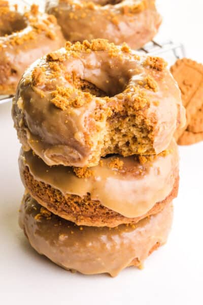 A stack of biscoff donuts shows the top one with a bite taken out.