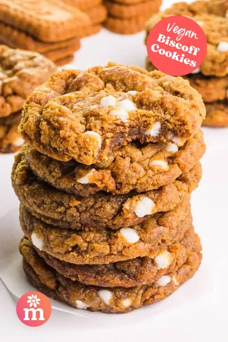 A stack of cookies shows the top one with a bite taken out. There are more cookies in the background. The text reads, Vegan Biscoff Cookies.
