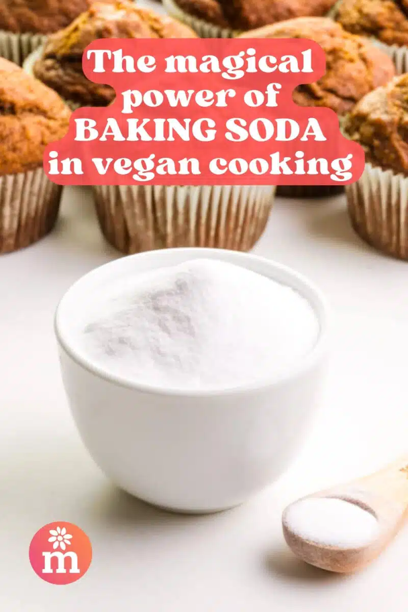 A small bowl of white powder has a measuring spoon beside it and muffins in the background. The text reads, The Magical Power of Baking Soda in Vegan Cooking.