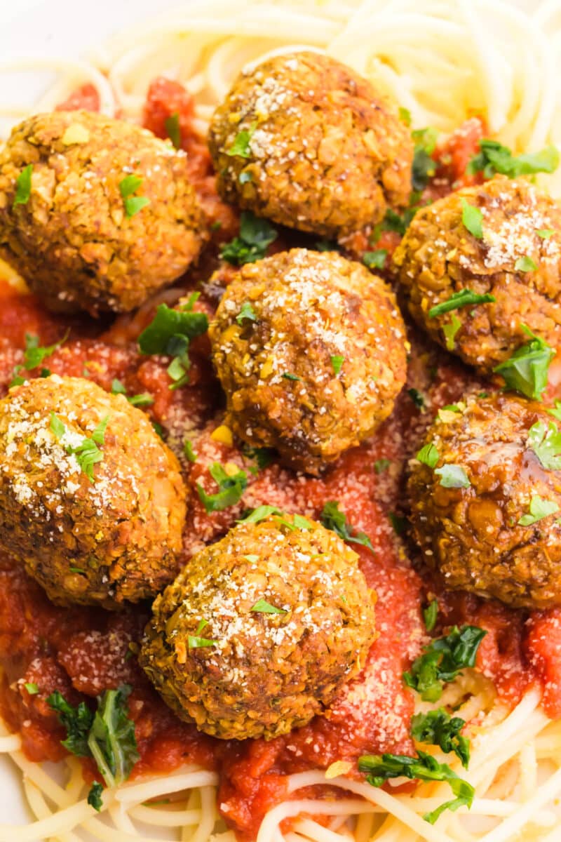 Chickpea balls rest on top of pasta with marinara sauce.