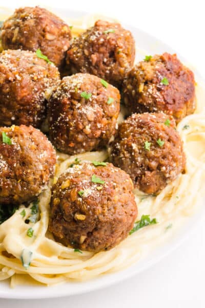 A plate of pasta with cream sauce is topped with several Impossible Meatballs.