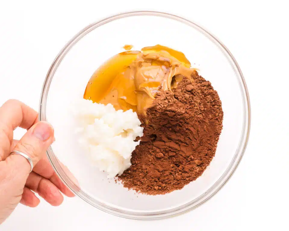 Coconut oil, coco powder, peanut butter and other ingredients are in a mixing bowl.