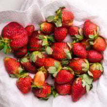 A bunch of strawberries are drying on a plate lined with paper towels.