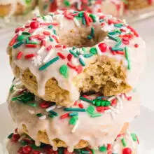 A stack of vegan Christmas donuts shows the top one with a bite taken out.