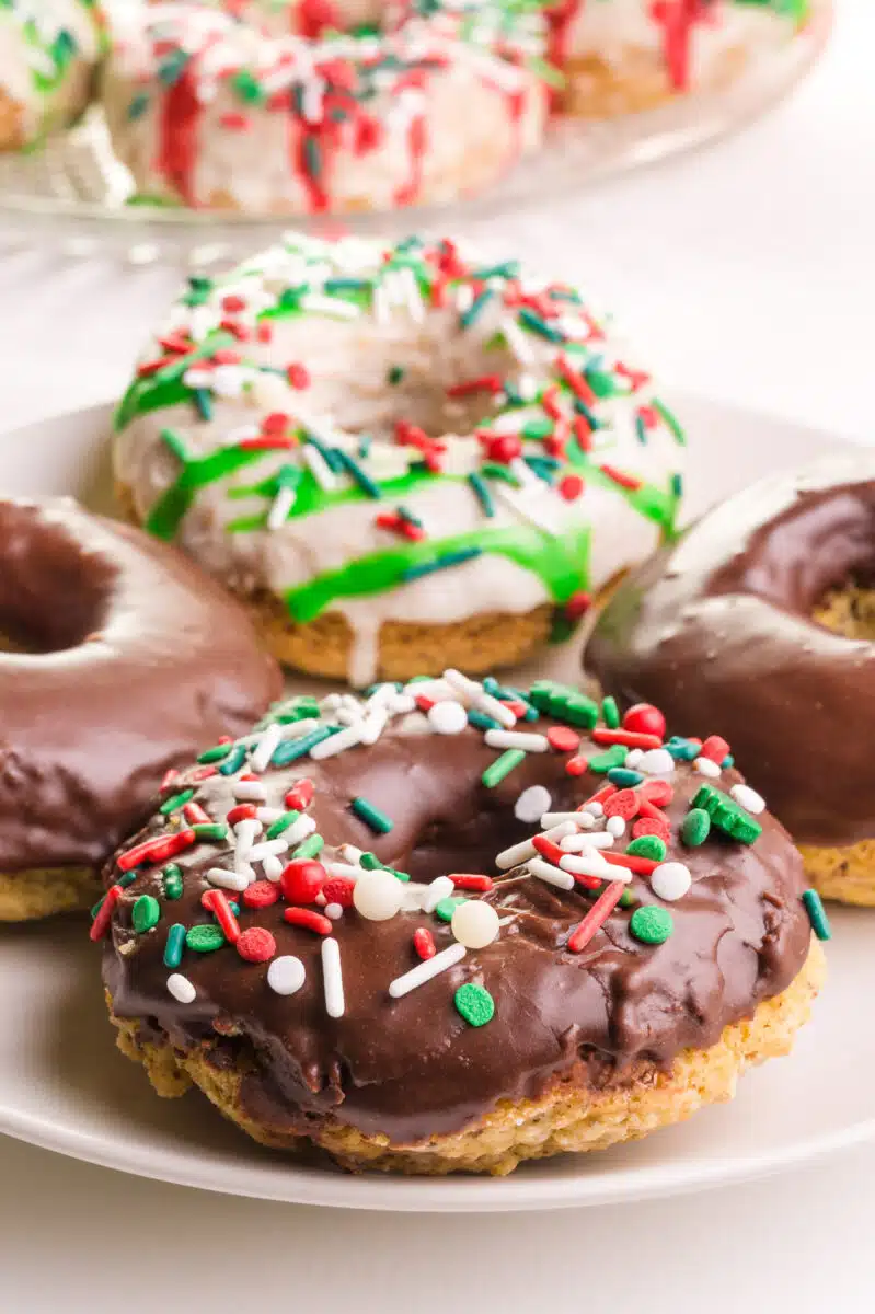 A plate of baked donuts sit on a plate. Some are frosted with white icing and others have chocolate icing.