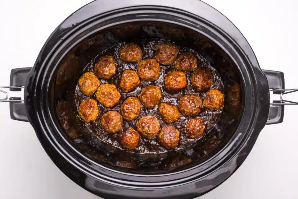 Looking down on a crockpot full of sauce and vegan meatballs.