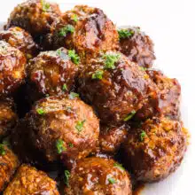 Vegan grape jelly meatballs are stacked high on a plate.