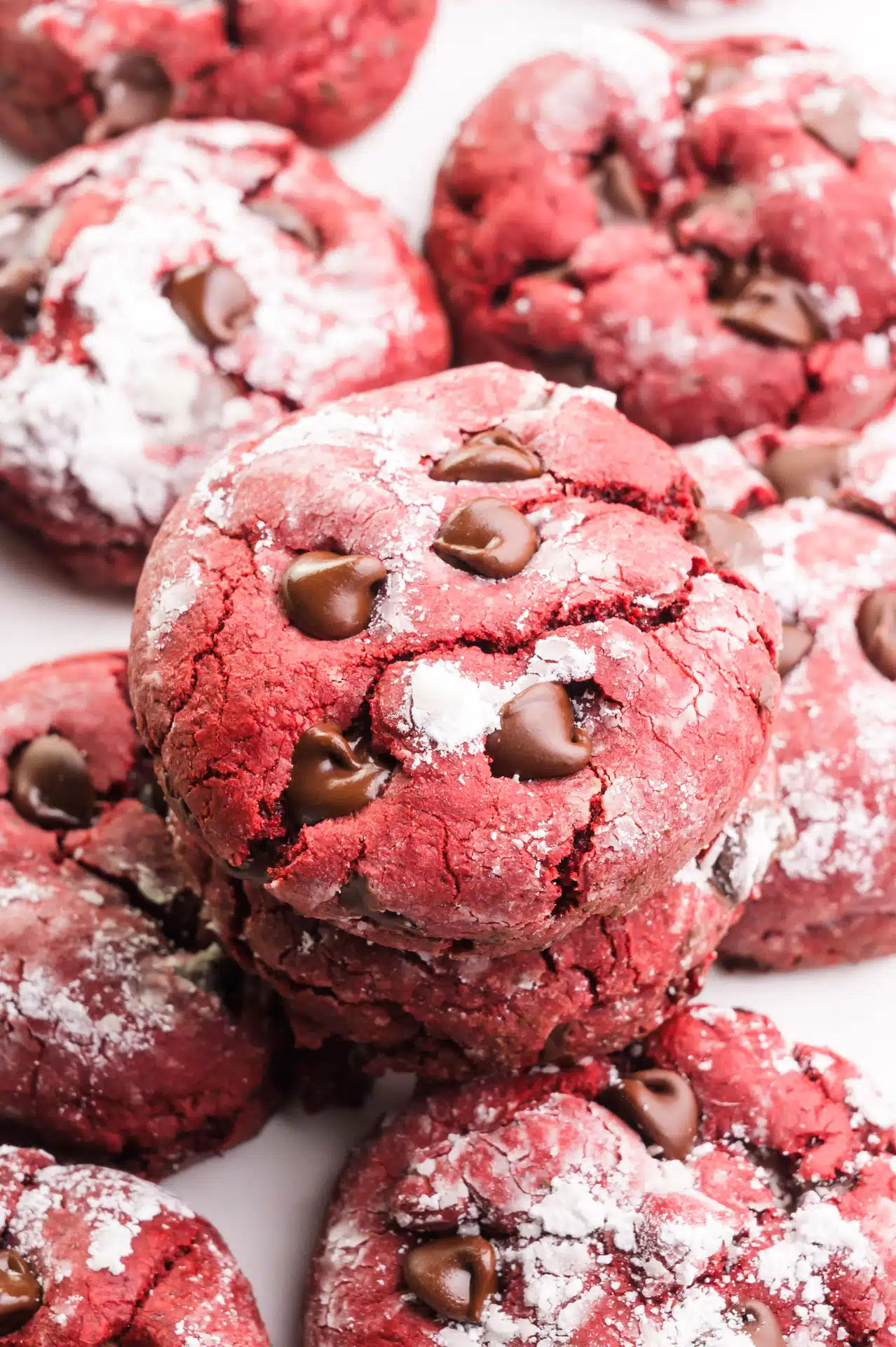 Chocolate Chip Red Velvet Cookies are stacked and surrounded by other cookies.