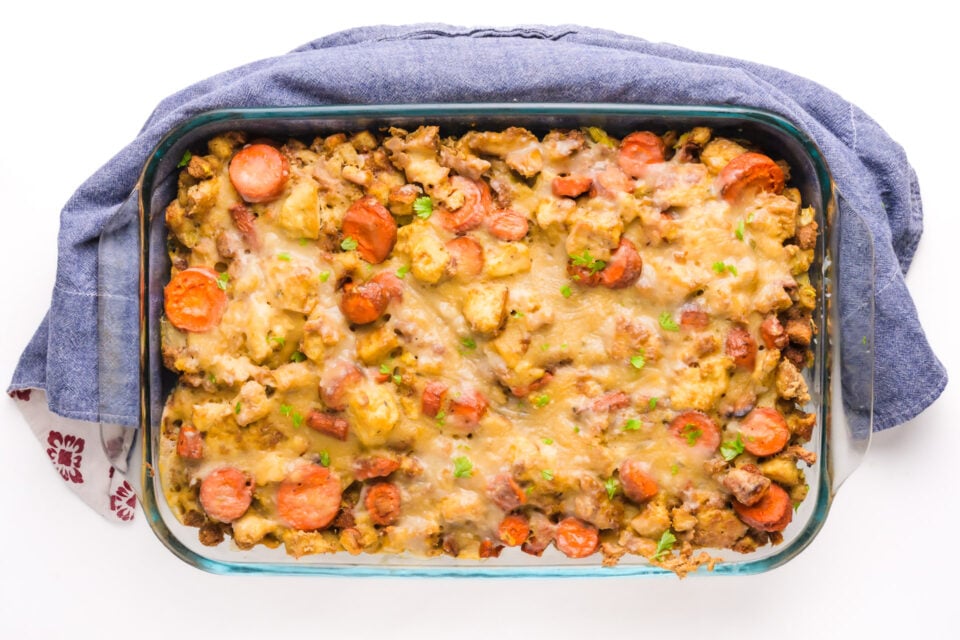 Looking down on a casserole dish full of vegetarian holiday casserole. There's a blue kitchen towel around it.