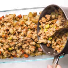 Stuffing is being poured from a saucepan into a baking dish.