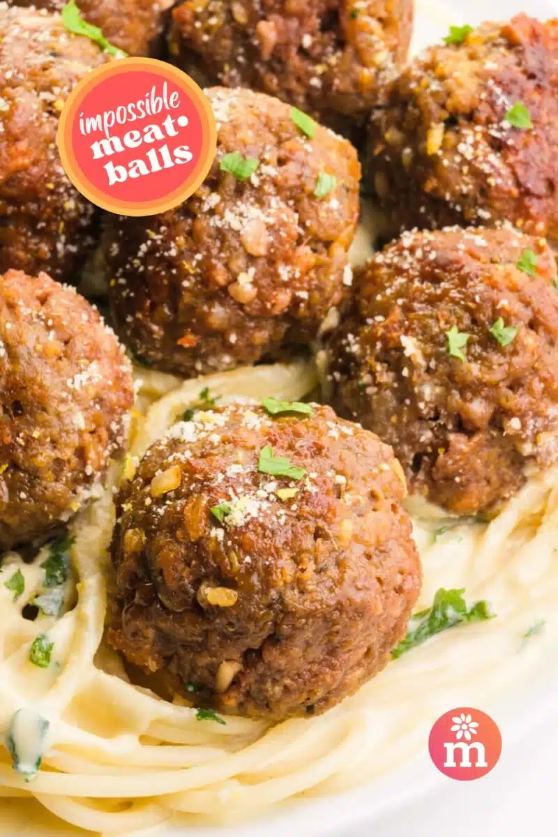 Delicious plant-based Impossible Meatballs served on a bed of flavorful spaghetti pasta – a satisfying vegan twist on a classic favorite. Text overlay: 'Impossible Meatballs.'