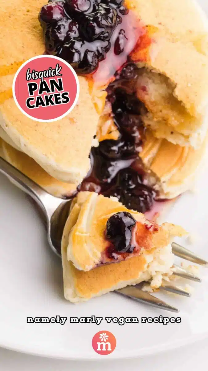 Looking down on a stack of pancakes with blueberries and syrup on top. There is a bite taken out and sitting on a fork. The text reads, Bisquick Pancakes, Namely Marly Vegan Recipes.
