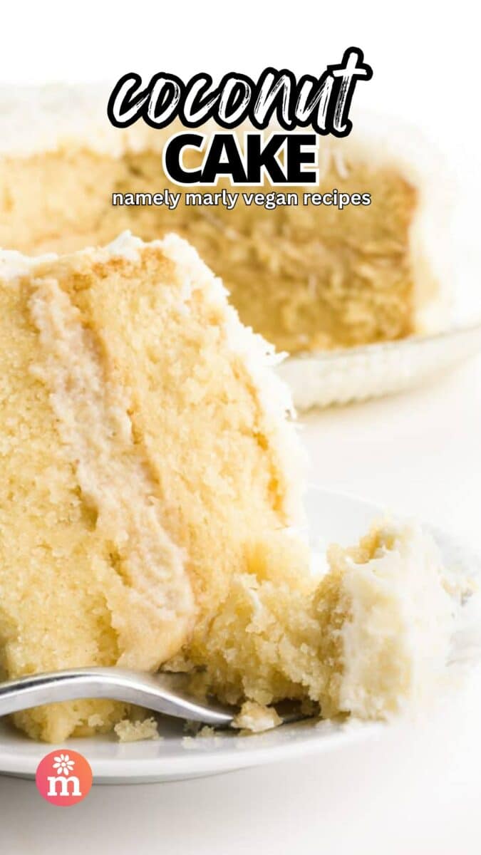 A slice of coconut cake sits on a plate with a bite taken out sitting on a fork. The rest of the cake is in the background. The text reads, Coconut Cake, Namely Marly Vegan Recipes.