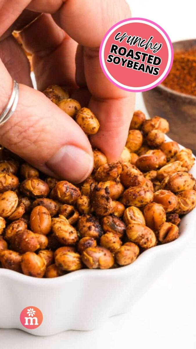 A hand grabs roasted beans from a bowl. The text reads, Crunchy Roasted Soybeans.
