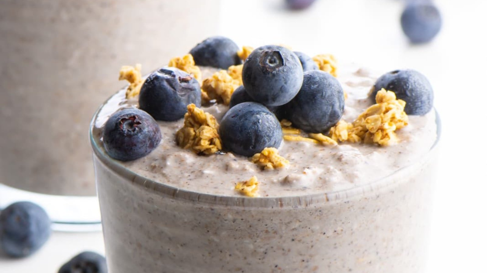 A closeup of vegan blueberry overnight oats shows granola and fresh blueberries on top.