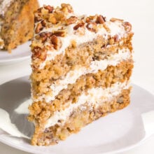 A slice of hummingbird cake on a plate has frosting on top and between the layers.