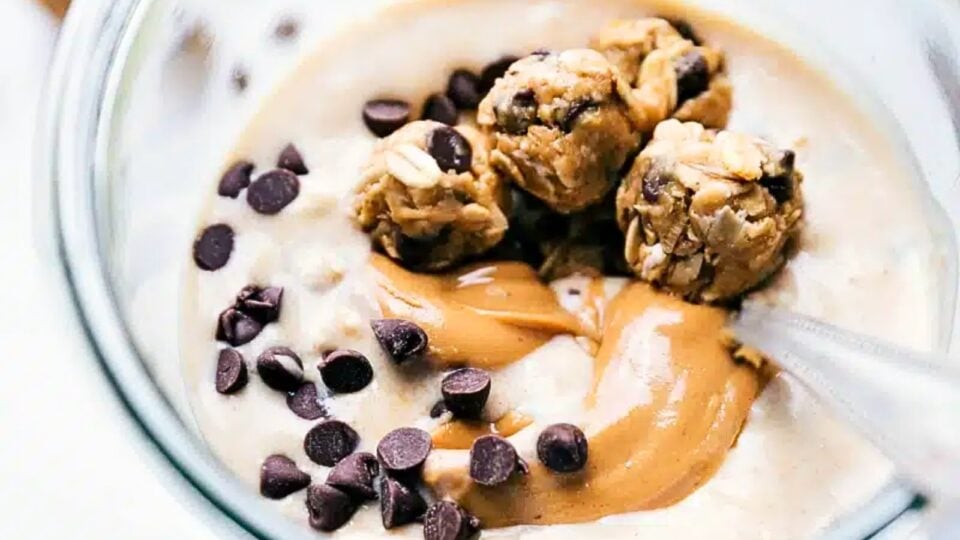 Looking down on a jar of overnight oats with mini cookie dough balls, peanut butter swirls, and chocolate chips on top.
